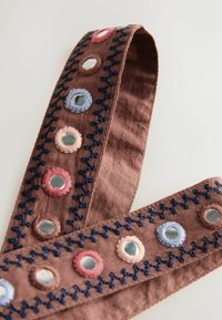 Ceinture en tissu marron avec des ornements ronds en miroir cousus avec un fil de couleur pastel et des surpiqûres en zigzag bleu foncé le long des bords.