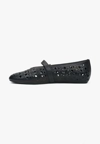 Czarne płaskie buty wykonane z perforowanego materiału z wyciętymi wzorami, z paskiem na górze i butem w szpic.