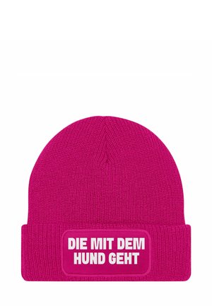 Fuchsia gestrickte Mütze mit dicker Bündchen, die ein rechteckiges weißes Patch mit schwarzem Text trägt, auf dem steht "DIE MIT DEM HUND GEHT."