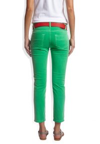 Jeans de mezclilla verdes con un corte slim, diseño de cinco bolsillos y un acento de cinturón rojo. Textura suave con un ligero desvanecimiento alrededor de los bolsillos.
