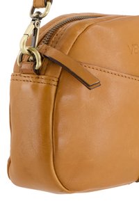 Brązowa skórzana torebka na ramię z zamknięciem na zamek, złotymi metalowymi detalami i gładką fakturą. Posiada boczny pasek akcentujący dla stylu.