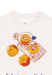 Witte t-shirt met een oranje en gele grafische afbeelding van perziken, met een label dat "perziken" leest en een ontwerp van een houten snijplank.