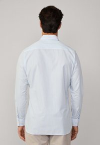 Chemise à rayures bleu clair et blanche à manches longues, avec un col standard et des poignets à boutons. Tissu lisse avec une coupe cintrée.