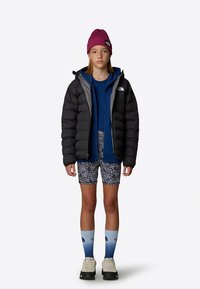 Juoda pūkinė striukė dėvima ant mėlynos gobtuvu džemperio. Sportinės trumpos kelnės su baltais raštais. Rožinė megzta kepurė. Mėlynos gradientinės kojinės. Pilki lauko batai.