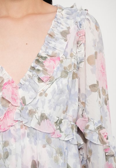 Bluza florală în culori pastelate, cu margini volanate în roz, albastru și verde. Material ușor, transparent, cu decolteu în V.