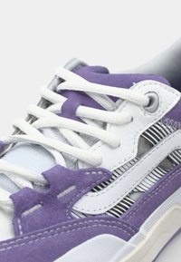 Zapatillas moradas y blancas con cuero texturizado y malla, que cuentan con acentos estampados, cordones gruesos y un cuello y lengua acolchados.