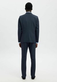 Granatowy garnitur z fakturowanej tkaniny, charakteryzujący się dopasowanym krojem i slim fit. Zawiera długie spodnie i marynarkę z klapami.