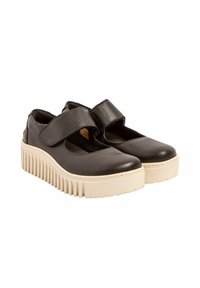 Zapatos de cuero negro con correas ajustables, punta redonda y una gruesa suela de plataforma blanca con estrías verticales.