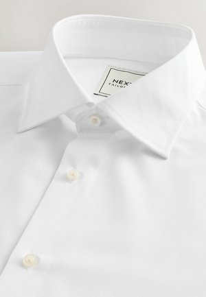 Witte overhemd gemaakt van gladde stof, met een klassieke spread collar, drie knopen op de pat, en een merketiket aan de binnenkant van de kraag.