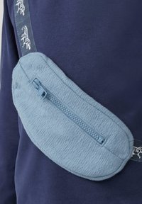 Hellblaues Stofftäschchen mit strukturierter Oberfläche, ausgestattet mit einem Reißverschluss und einem gemusterten Tragegurt mit kontrastierenden Designelementen.
