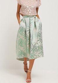 Gonna a campana di lunghezza al ginocchio in tessuto leggero con motivo a foglie verde menta e argento, con tasche laterali e vita legata.