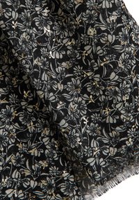 Tissu noir avec un motif floral en tons d'argent et d'or. Comprend différentes formes de fleurs et des détails délicats, avec un bord effiloché.