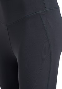 Czarne legginsy o gładkiej teksturze, z płaskimi szwami dla komfortu i dopasowanym kroju. Bez widocznych wzorów ani akcentów.