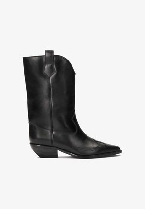 Bota vaquera de cuero negra con punta afilada, caña de altura media y costuras decorativas. Cuenta con un tacón bajo y cuadrado y una asa lateral.