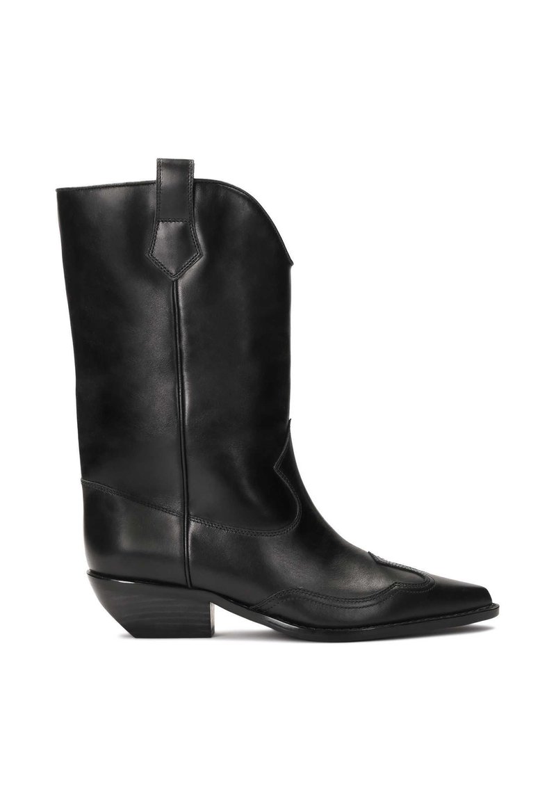 Bota vaquera de cuero negra con punta afilada, caña de altura media y costuras decorativas. Cuenta con un tacón bajo y cuadrado y una asa lateral.
