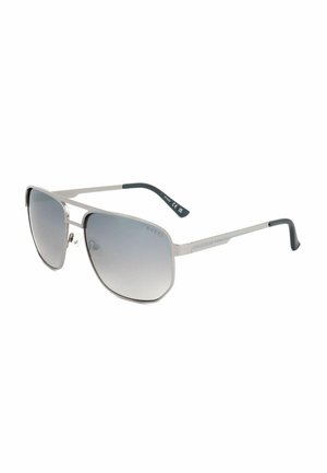 Occhiali da sole aviator Guess con montatura in metallo argento, lenti sfumate grigie e terminali neri alle aste, inclinati su sfondo bianco.