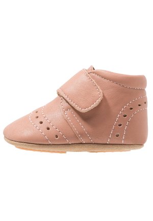 Pink leather shoe with a Velcro strap, rounded toe, side perforations, and light brown rubber sole. Smooth texture and minimalist design.
