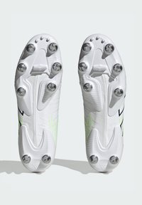 Botas de fútbol blancas con una superficie texturizada, costuras detalladas y tacos metálicos. Presentan un diseño de acento verde en los lados.