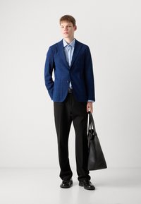 Modra karirana blazer s razrezanimi reverji, svetlo modra srajca, črne hlače, črne usnjene čevlje in črna torba.