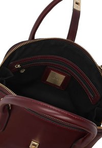 Burgundy läderhandväska med guldfärgade detaljer, med dragkedjestängning och svart tygfoder, inkluderar interna fickor för organiserad förvaring.