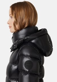 Czarna kurtka puchowa z wysokim kołnierzem i kapturem. Posiada pikowany design, błyszczącą teksturę oraz naszywkę z logo na lewym rękawie. Zapięcie na suwak z przodu.