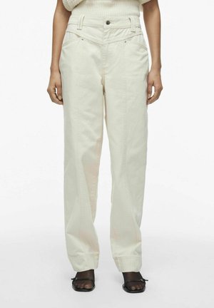 Pantalones de mezclilla de pierna ancha en color beige claro. Cuenta con bolsillos clásicos, una cintura alta y detalles de costura visibles. Diseño de frente plano.