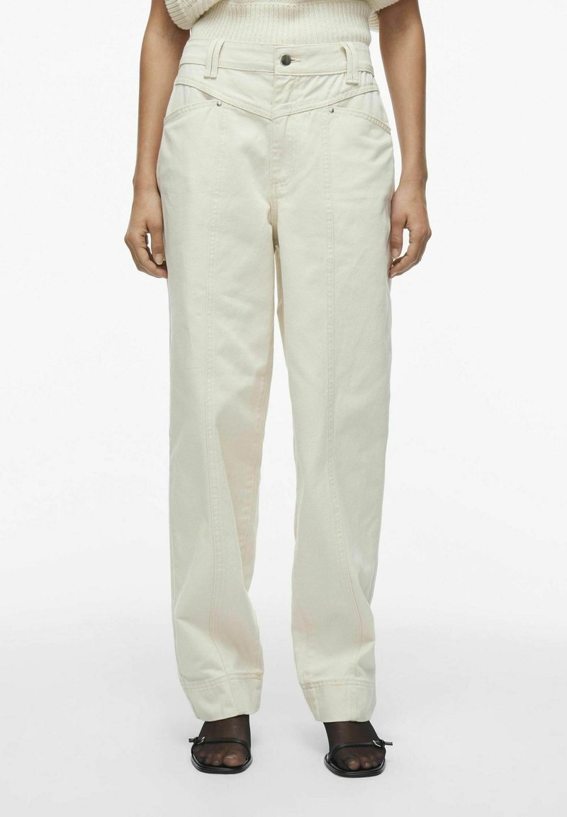 Pantalones de mezclilla de pierna ancha en color beige claro. Cuenta con bolsillos clásicos, una cintura alta y detalles de costura visibles. Diseño de frente plano.