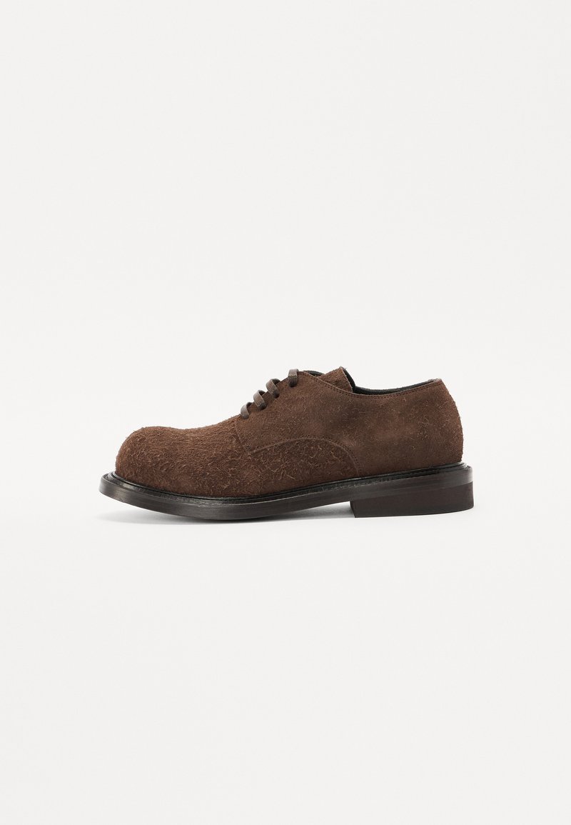 Brown suede lace-up shoe with a textured surface, rounded toe, short heel, and a flat black sole.