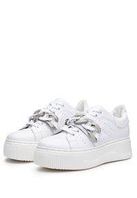 Sneakers bianchi con suola spessa, parte superiore in sintetico liscio, dettagli perforati e accenti in catena metallica sui lacci.