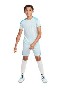Maglia sportiva azzurro chiaro con accenti blu scuro, pantaloni corti abbinati e calze bianche al ginocchio. Presenta il logo Nike sulla maglia e sulle scarpe.