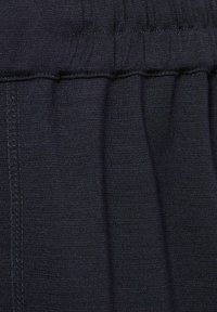Material negru cu o suprafață netedă, puțin texturată. Are un elastic la talie cu detalii îngrijite și o croială dreaptă.