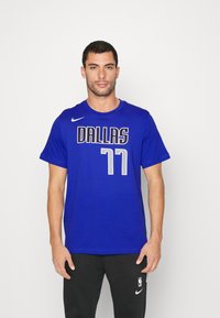 Blå bomull T-skjorte med "DALLAS" og "77" trykket i hvitt, kort ermer, med rund hals og Nike-logo på venstre bryst.