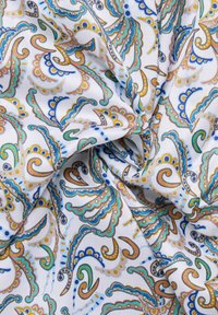 Tessuto a fantasia con sfondo bianco, caratterizzato da vivaci design paisley in blu, verde, arancione e marrone, con dettagli intricati e spirali.