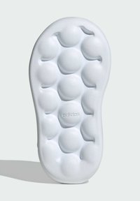 Biela podrážka tenisky s vyvýšenými kruhovými vzormi. Hladký povrch s vyrazeným logom "adidas". Zaoblené okraje a kontúrovaný tvar.