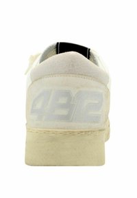 Sneaker bianco con una finitura testurizzata, dotata di un tallone imbottito, un accento nero sul collo e un logo "4812" stampato delicatamente sul retro.