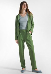 Grøn hættetrøje og matchende bukser med en tekstureret finish; lyseblå tanktop og lyseblå ballet flats med knudedetalje.