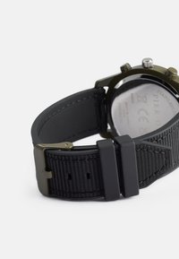 Μαύρο ρολόι με υφασμάτινο λουράκι; ανοξείδωτη ατσάλινη θήκη και κούμπωμα; περιλαμβάνει λεία πλάτη, κομψά κουμπιά και καθαρές ενδείξεις.