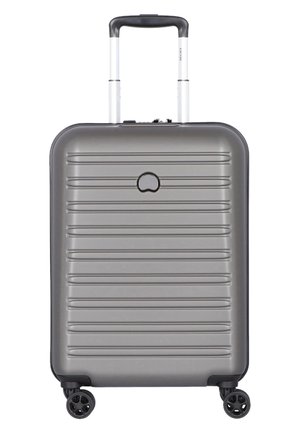 Hard-shell, gray suitcase with a ribbed design, telescopic handle, and four black wheels. Features a minimalist logo on the front.