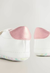 Pantofi din piele albă cu un toc lucios roz și o talpă texturată cu model multicolor. Formă rotundă, design simplu.