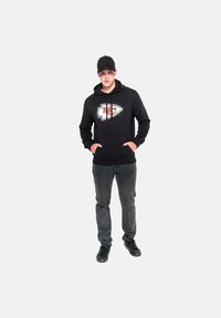 Felpa nera con logo rosso e bianco, tasca frontale e cordoncino. Abbinata a jeans grigio scuro e sneaker nere. Design semplice e casual.
