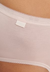 Heller rosa nahtloser BH mit einer weichen Textur. Verfügt über einen zarten Spitzenbesatz entlang der oberen Kante und ein kleines Markenetikett, das seitlich eingenäht ist.