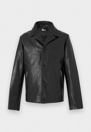 Zwarte leren jas met knopen, puntige kraag en ritszakken aan de zijkant, weergegeven tegen een neutrale achtergrond.