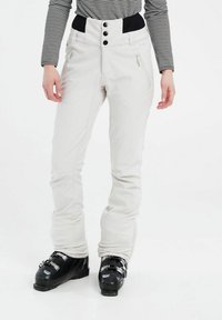 Witte skibroek met een aansluitend ontwerp, voorzien van een brede zwarte tailleband, drie zwarte knopen en ritssluitingen in de zakken. Gemaakt om te gedragen met zwarte skischoenen.