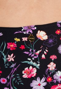 Top de bikini florido em preto com padrões de flores coloridas. Inclui um pequeno detalhe metálico dourado com o nome da marca "Lascana."