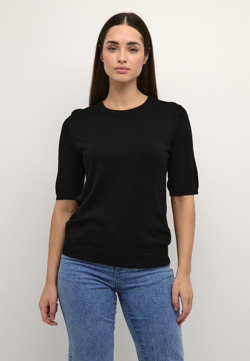 Maglione nero a maniche corte con scollo tondo e orlo a costine. Design aderente, realizzato in materiale morbido, abbinato a jeans blu.