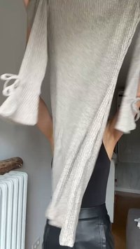 Pulover lung, cu nervuri, de culoare gri deschis, cu mâneci ample și detalii cu legături la mansete. Textură moale, siluetă alungită. Potrivit pentru stratificare.