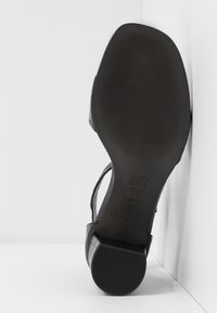 Semelle d'une chaussure en cuir noir avec une semelle texturée, un petit talon bloc et la taille 4 ½ visible en dessous.