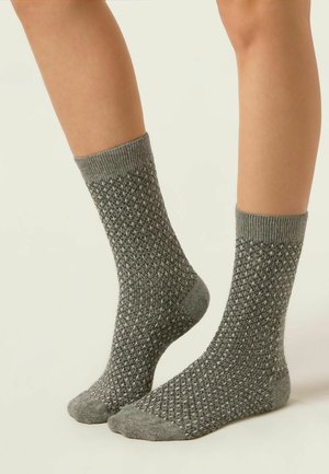 Chaussettes en tricot grises avec un motif texturé, une bordure côtelée et un talon renforcé. Conçues pour le confort et la chaleur.