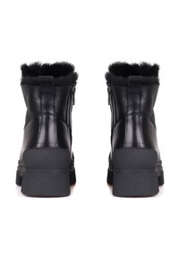 Botas de tobillo de cuero negro con un cuello de pelo sintético, cierre de cremallera lateral, suela de goma resistente y patrón texturizado en el tacón.