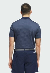 Navy polo shirt with a textured pattern, short sleeves, and a collar, paired with navy shorts and a gray woven belt.